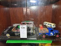 Photo showing a black classic car, a silver vintage car, a blue USMC truck with wooden side rails, and a white and blue bus.