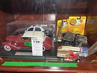 Multiple die cast cars including a vintage 1937 Lincoln Zephyr Police Cruiser, a red farm truck with wooden block bed, Speed Wheels cars in package, and other toy vehicles on display