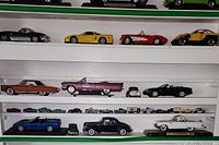 Shelf showing a collection of about 30 die cast cars of various makes, styles, and colors including classic cars, sports cars, and convertibles.