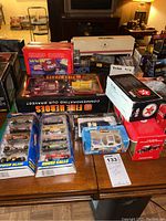 Front view of the lot showing multiple boxed die cast vehicles including Hot Wheels 5-packs, Fire Heroes fire truck set, airplane model, Texaco gas pump box, and other assorted die cast models.
