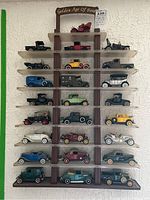 Full collection of 20 Ford die cast model cars displayed on the multi-tier shelf mounted on a wall.