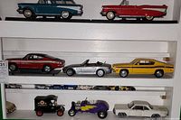 Shelf with multiple die cast car models including classic cars and trucks in various colors.