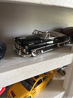 Black classic convertible die cast car on a white shelf
