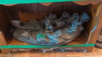 Wooden sculpture of figures in a canoe on water, showing detailed carving and wood texture on the base.