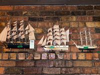 Three model ships displayed on a brick wall showing varied sizes and styles.