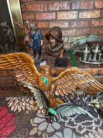 Western themed statues and eagle wall sculptures arranged on floor and shelf against brick wall
