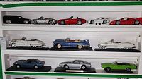 Three shelves of die cast vehicle models arranged with visible display bases and shelves, showing colors and details of cars from SUVs to sports cars.