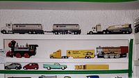 Full shelf display of various toy vehicles including Chevron tanker truck, Kodak truck, black train, and assorted cars