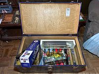 Open blue storage trunk showing lined interior and boxed Packard die cast cars including Outdoor Life models and Mobil 1 box.