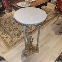 Front view of 1920s marble and gold round table showing marble top and three fluted legs attached to gold detailed base.
