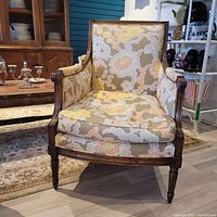 Front view of the single upholstered chair showing floral patterned fabric and wooden frame with carved details.