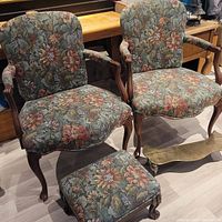 Two floral upholstered chairs with carved wooden frame and a matching footstool. Small brass footstool placed in front.