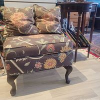 Footstool with floral fabric and two matching floral pillows placed on top, showing colors and fabric pattern