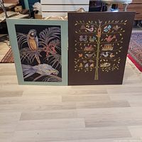 Front view of two framed bird-themed hanging pictures, one with parrots, the other with a bird tree design