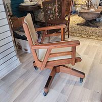 Side view of chair showing wood frame, armrests, seat and wheels