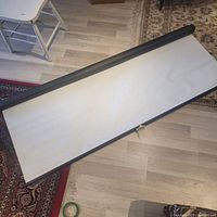 Projection screen fully unrolled on floor showing surface and black borders.