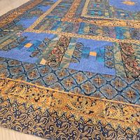 Close-up showing detailed floral and geometric patterns in blue and gold fabric of the quilt.