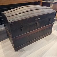 Front and side view of the vintage wooden treasure chest showing worn metal bands, curved top and lock mechanisms.