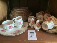 Various pieces of Royal Albert "American Beauty" china including plates, cups, creamer, sugar bowl, salt and pepper shakers with rose pattern and gold trim.