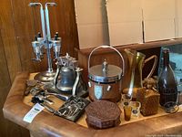 Lot items displayed on a table showing multiple barware and liquor accessories including liquor dispenser, ice bucket, decanter, glasses, bottle openers, and wooden box.