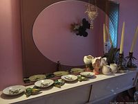 Wide shot of all items on a dresser with mirror showing candle holders, small ceramic birds, floral vase, small pitcher, and decorative plate.