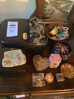 Overview of large black jewelry case, embroidered case and assorted trinket boxes