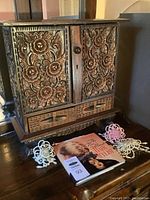 Full view of carved wooden jewelry box closed on tabletop with hair scrunchies and book in front