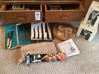 J.A. Henckles knives and cutting utensils, wooden condiment holder, lace doilies, and napkins on carpet in front of sideboard