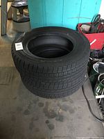 Two black Dunlop snow tires stacked, showing tread pattern and general condition.
