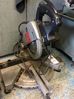 Full view of Elu mitre chop saw on a floor, showing the handle, blade, and base with angle markings.
