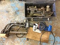 Overview of lathe packed in plastic toolbox with separate chain saw sharpener assembly mounted on plywood