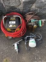 Overall view of sprayer unit, pressure tank, red hose, spray gun and container