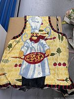 Apron with chef, pizza, and food-themed print, showing colors and design details