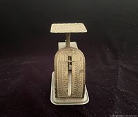 Front view of antique Crescent postage scale showing detailed postage rates and the sliding weight indicator.