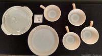Lot includes covered casserole, divided plate, and four cups with handles in peach color.