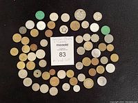 Top-down view of 53 assorted foreign coins and miscellaneous tokens arranged around a note indicating 'Foreign Coins + Tokens, Mixed Lot'.