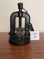 Front view of black cast iron pipe vice with screw clamp and jaws, placed on wooden surface.