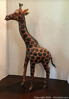 Front and side view of a handcrafted wooden giraffe sculpture displaying its painted spots and standing posture.