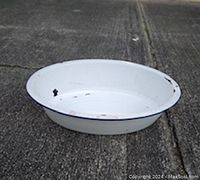 Photo of a large round white enamel basin on a concrete floor showing some wear and chipped areas