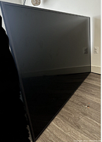 Front view of the 84-inch Samsung TV leaning against a wall showing the screen and bezel