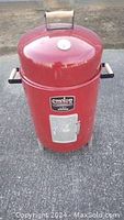 Photo of the full red vertical drum smoker with lid and wooden handles outdoors