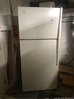 Full view of white Admiral top-freezer refrigerator showing front side in a basement setting.