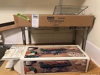 Two Uline chrome wire shelves one stacked over the other, smaller chrome rack in front, hot stone grill boxed on top of shelves