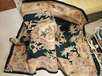 View of the rug spread with visible floral and border pattern and fringe at one side.