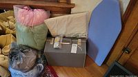 Multiple bags containing fabric remnants and sewing accessories around a closed grey sewing machine case.