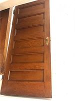Front view of the vintage solid oak door showing six shaker panels and brass hardware