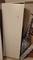 Front side view of white Ikea wardrobe cabinet in storage setting.