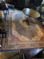 Full view of the modern Oriental style rug with a wooden pedestal table placed on top.