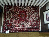 Top view of rectangular oriental rug showing entire pattern and some surrounding floor and furniture.