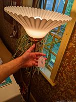 Photo of the brass torchiere floor lamp turned off, showing the shell-style fluted white glass shade and polished brass finish of the lamp pole and holder.